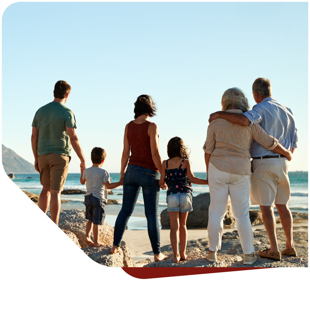 Darstellung einer Familie, die Arm in Arm an einem Meeresufer steht. Zeigt Zusammenhalt der versch. Generationen.