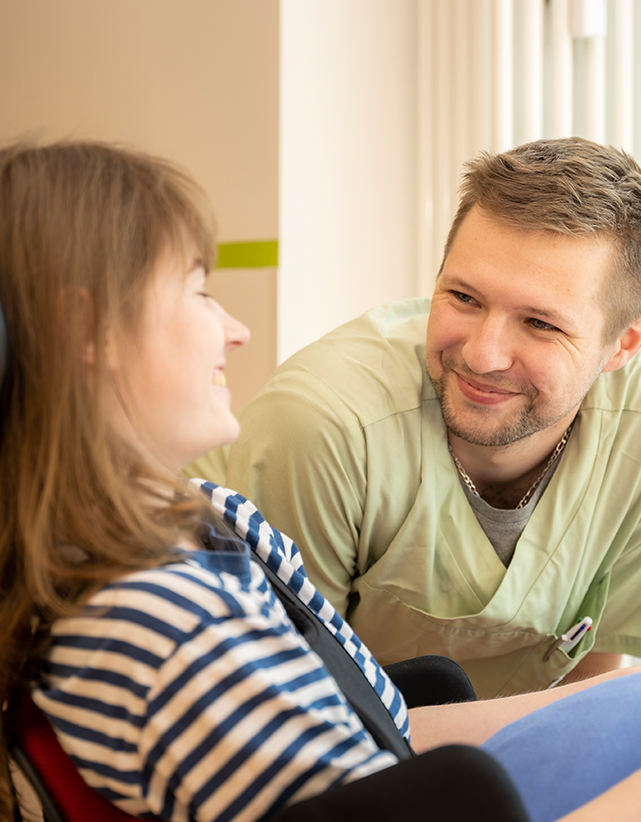 Gespräch zwischen Pfleger und Patientin, beide lächeln