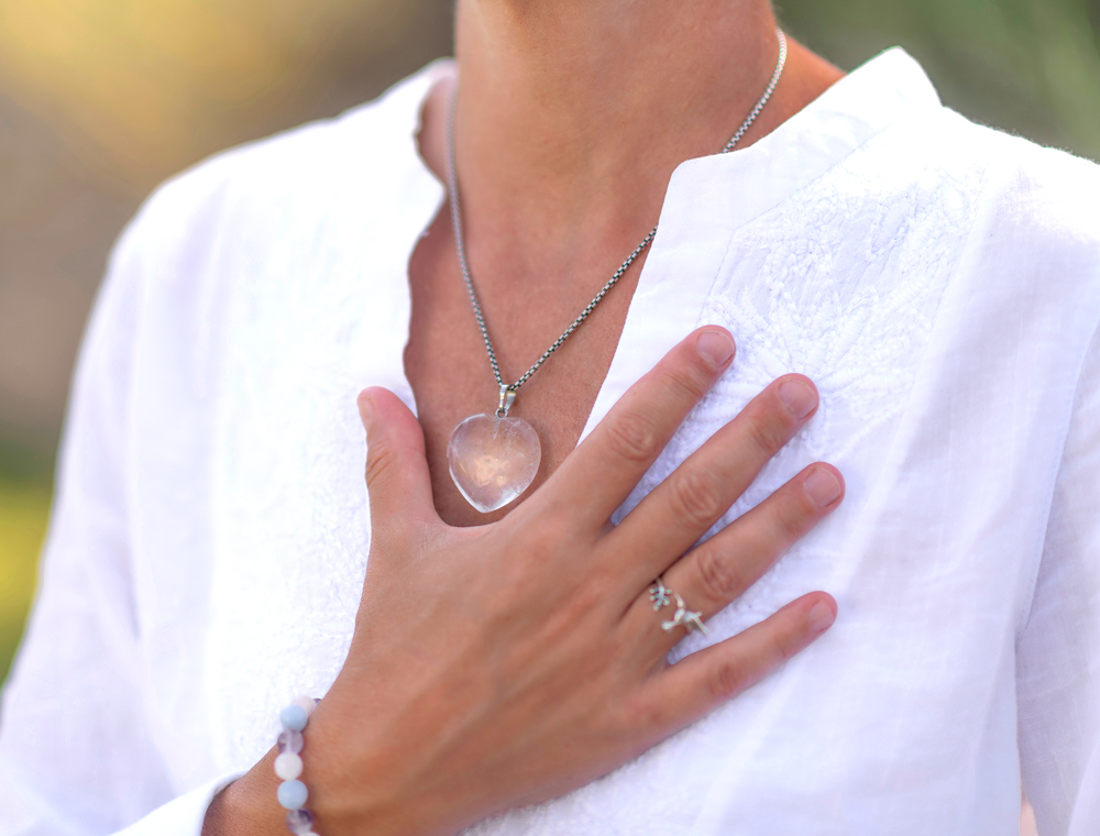 Eine Person hält die Hand auf die Brust mit einem Herzanhänger, symbolisierend Herzgesundheit, Wohlbefinden und das Vertrauen in die fürsorgliche Betreuung durch Pielmeier Medizintechnik.